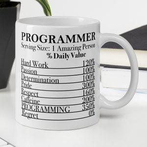 May include: White ceramic mug with a black graphic that reads "PROGRAMMER" and lists the daily value percentage of hard work, passion, determination, pride, respect, caffeine, programming, and regret.