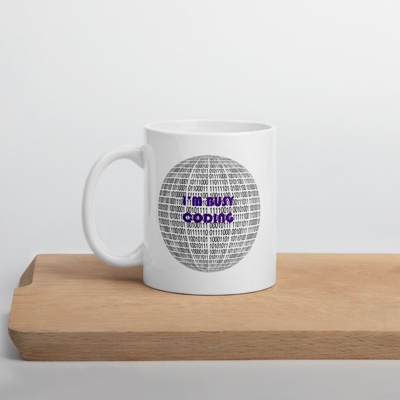 May include: White ceramic mug with a black and white binary code design. The text "I'm busy coding" is in purple on the mug.