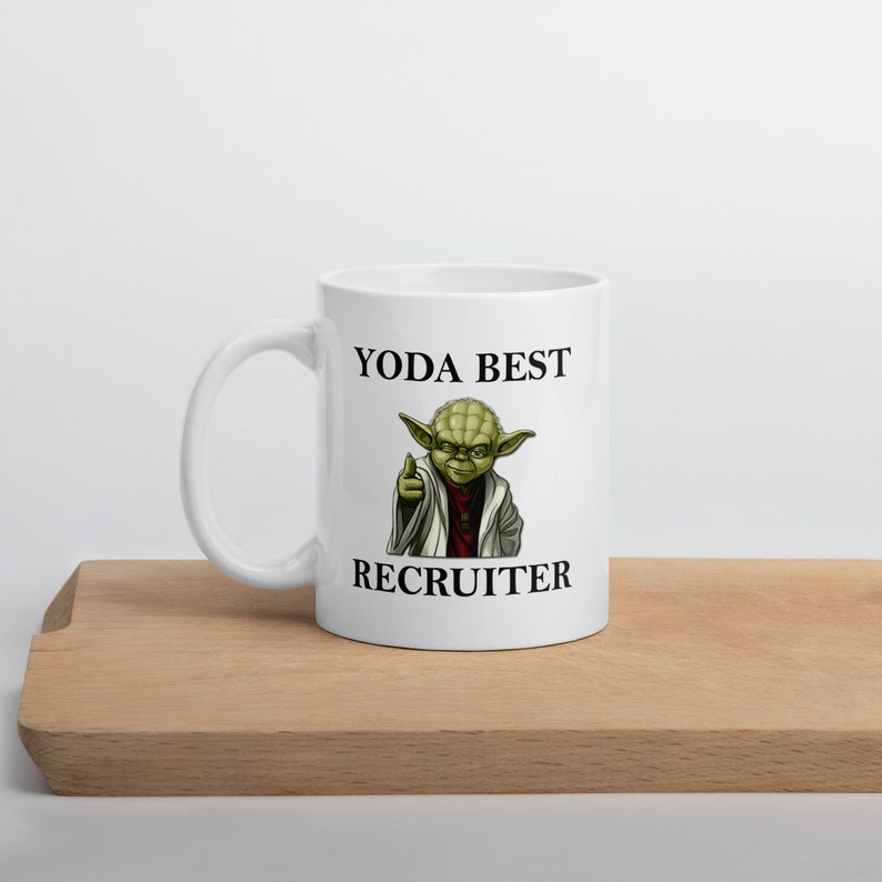 Pu&ograve; includere: Una tazza in ceramica bianca con un personaggio verde di Yoda che punta verso lo spettatore. Il testo "YODA BEST RECRUITER" &egrave; stampato sulla tazza.