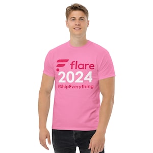 May include: Pink t-shirt with a white logo that says "flare 2024 #ShipEverything"