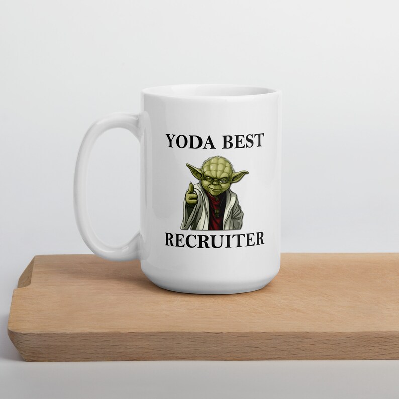 Pu&ograve; includere: Tazza in ceramica bianca con un personaggio verde di Yoda e il testo "YODA BEST RECRUITER".