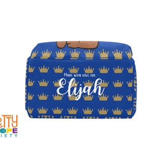 Puede incluir: Una bolsa de almuerzo azul con un patr&oacute;n de coronas doradas. El nombre "Elijah" est&aacute; escrito en blanco, con el texto "Made with love for:" encima. La bolsa es de la marca "Pretty Dope Society".