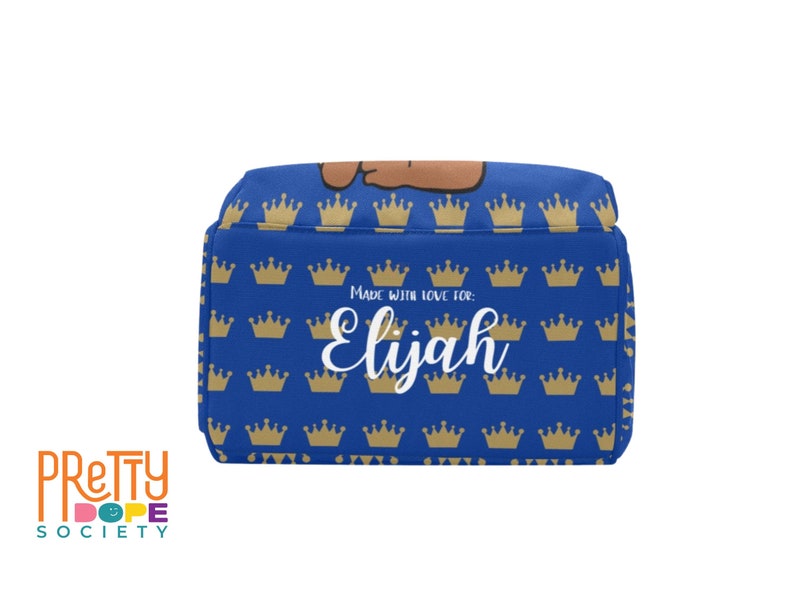 Puede incluir: Una bolsa de almuerzo azul con un patr&oacute;n de coronas doradas. El nombre "Elijah" est&aacute; escrito en blanco, con el texto "Made with love for:" encima. La bolsa es de la marca "Pretty Dope Society".