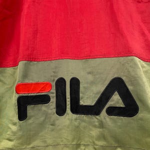 Op de afbeelding: Rood en groen nylon jack met een zwart FILA logo.