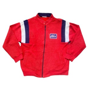 Op de afbeelding: Rood jack met rits met witte en donkerblauwe strepen op de mouwen. Het jack heeft een "Ford" logo-patch op de borst.