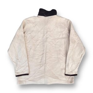 May include: A cream-colored fleece pullover with a black collar and black trim on the sleeves.