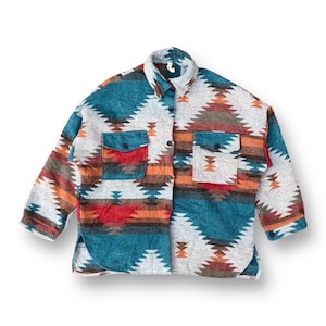 Puede incluir: Una camisa de franela con estampado de color azul verdoso, gris, rojo, naranja y marrón con cierre de botones y dos bolsillos de solapa.