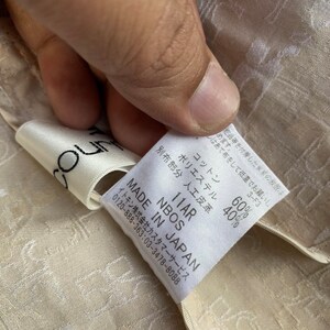 May include: A white tag with black text that reads "NBOS MADE IN JAPAN 11AR" and "60% Cotton, 40% Polyester". The tag also includes care instructions and a customer service phone number.