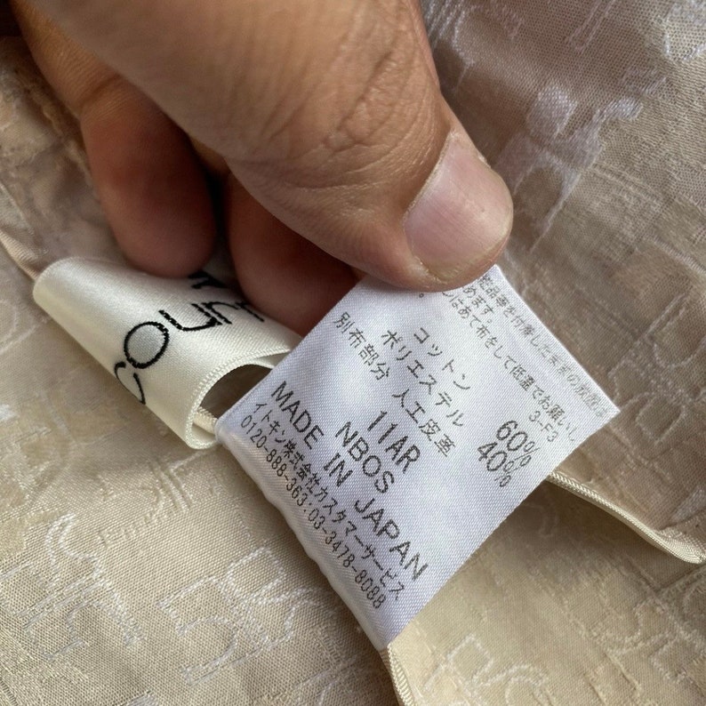 May include: A white tag with black text that reads "NBOS MADE IN JAPAN 11AR" and "60% Cotton, 40% Polyester". The tag also includes care instructions and a customer service phone number.