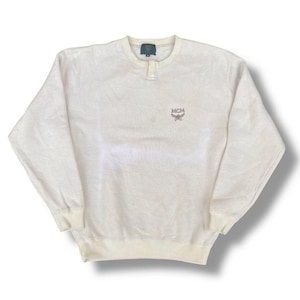 Puede incluir: Sudadera de manga larga color crema con textura acanalada. Cuenta con un pequeño cierre de botón en el cuello y el logotipo de MCM bordado en el pecho. Los puños y el dobladillo son de un color crema ligeramente más oscuro.