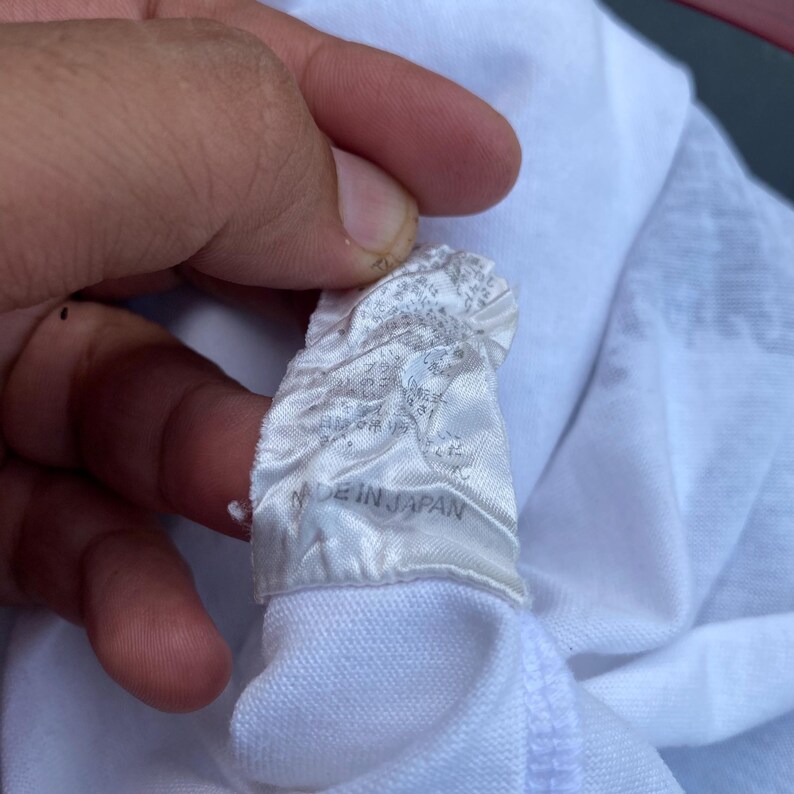 K&ouml;nnte beinhalten: Wei&szlig;es Etikett mit schwarzem Text, der "Made in Japan" lautet.
