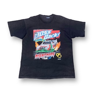 Könnte beinhalten: Schwarzes T-Shirt mit einem Aufdruck eines Rennwagens mit Flammen und dem Text "The Boss is Back! John Force Nightmare Tour '95".