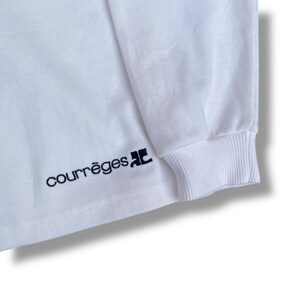 May include: White long-sleeve shirt with a ribbed cuff. The brand name "courr&egrave;ges" is embroidered in black script on the front. The shirt is made of a soft, comfortable material.