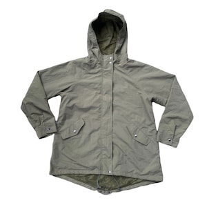 Può includere: Una giacca lunga con cappuccio, di colore verde oliva, con chiusura a zip e due tasche anteriori. La giacca ha un cordoncino in basso.