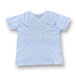 K&ouml;nnte beinhalten: Ein wei&szlig;es T-Shirt mit V-Ausschnitt und kurzen &Auml;rmeln.
