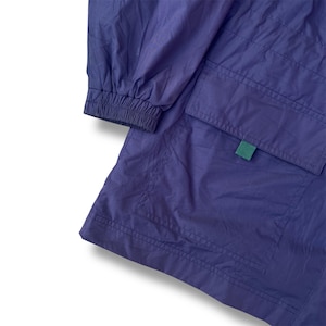 May include: Close-up of a purple jacket with a green tag and two pockets. The jacket has a gathered cuff and a quilted design. The fabric has a slight sheen.
