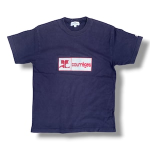 K&ouml;nnte beinhalten: Ein dunkelblaues Kurzarm-T-Shirt mit einer rechteckigen Grafik auf der Brust auf wei&szlig;em Grund, einem roten Logo und dem Schriftzug "courr&egrave;ges" in Rot. Das T-Shirt hat einen Rundhalsausschnitt und ein kleines wei&szlig;es Logo am linken &Auml;rmel.