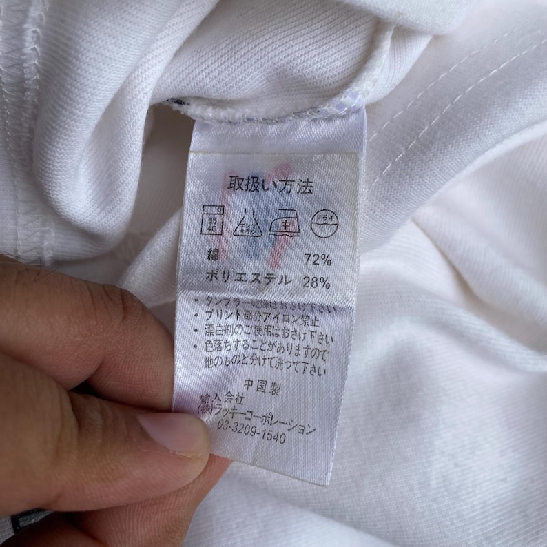 May include: A white fabric tag with Japanese text and care symbols. The tag lists the fabric composition as 72% cotton and 28% polyester. Additional text includes washing instructions and the manufacturer's information.