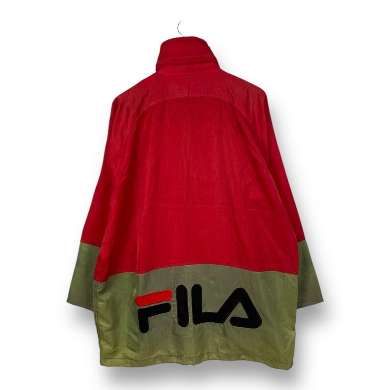 Op de afbeelding: Rood en groen Fila jack met een groot zwart Fila logo op de rug.