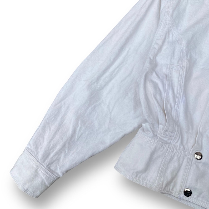 May include: White cotton jacket with a button closure and a pocket on the left side.