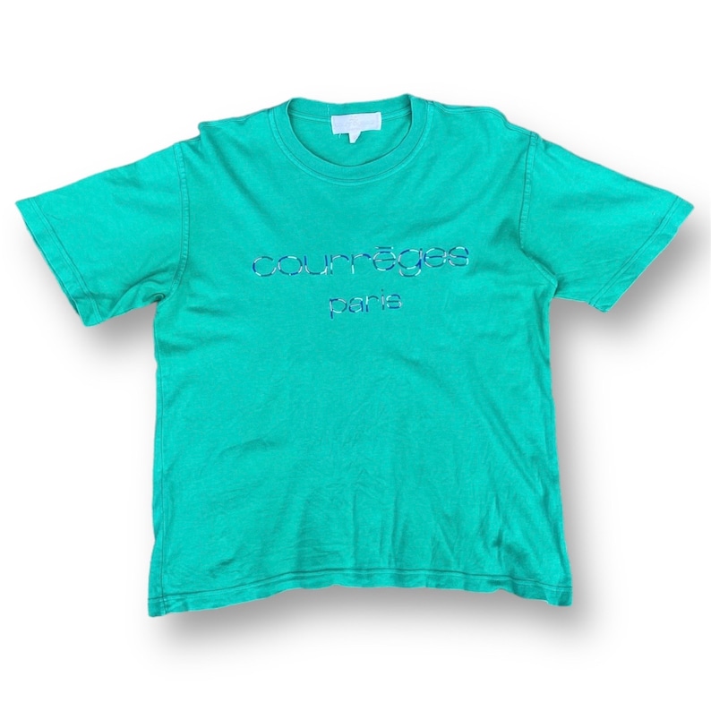 Puede incluir: Una camiseta azul turquesa con un logotipo blanco que dice "Courr&egrave;ges Paris" en una fuente azul y blanca.