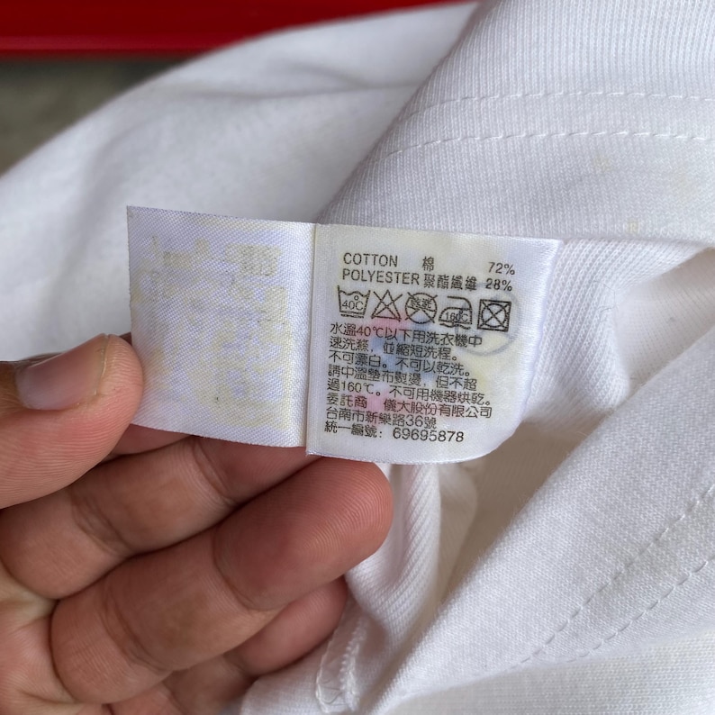 May include: A close-up of a white fabric tag with black text and care symbols. The tag indicates the fabric is 72% cotton and 28% polyester. Washing instructions include a 40&deg;C wash, no bleach, and no dry cleaning.