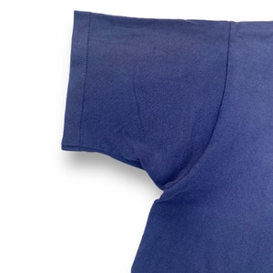 Puede incluir: Primer plano de la manga corta azul marino de una camiseta.