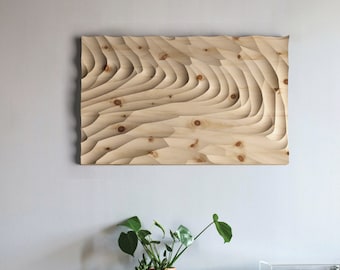 May include: A wooden wall art piece with a carved, layered design. The wood is a light brown color and the design is reminiscent of waves or ripples.