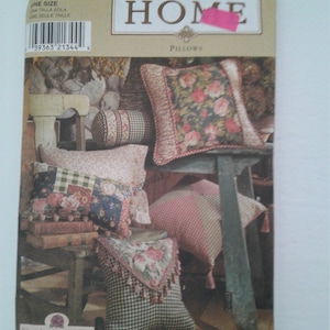 Puede incluir: Patrón de almohadas Simplicity Home, número de patrón 8044, con una foto de cuatro almohadas con diseños florales y a cuadros. Las almohadas están en una silla y un taburete de madera.