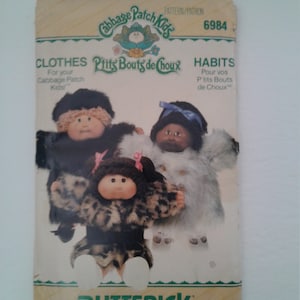 May include: A vintage sewing pattern for Cabbage Patch Kids clothing. The pattern is for making clothes for Cabbage Patch Kids dolls. The pattern is number 6984 and is called "P'tits Bouts de Choux" in French. The pattern includes instructions for making clothes for three different dolls.