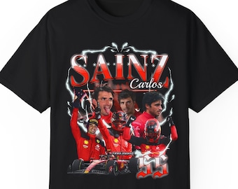 Op de afbeelding: Zwart T-shirt met een vintage-stijl grafische afbeelding van raceautocoureur Carlos Sainz Jr. in een rode raceauto. De afbeelding bevat de tekst "Sainz Carlos" en het nummer "55".