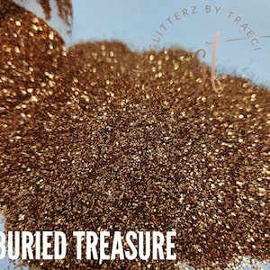 May include: A close-up of a pile of fine, sparkly, copper-colored glitter. The glitter is labeled "Buried Treasure" and is sold by Glitterz by Traeci.