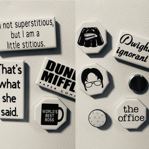 May include: A collection of white magnets with black text and graphics. The magnets feature quotes and images from the TV show "The Office," including "World's Best Boss" and character portraits. The magnets are arranged on a white surface.