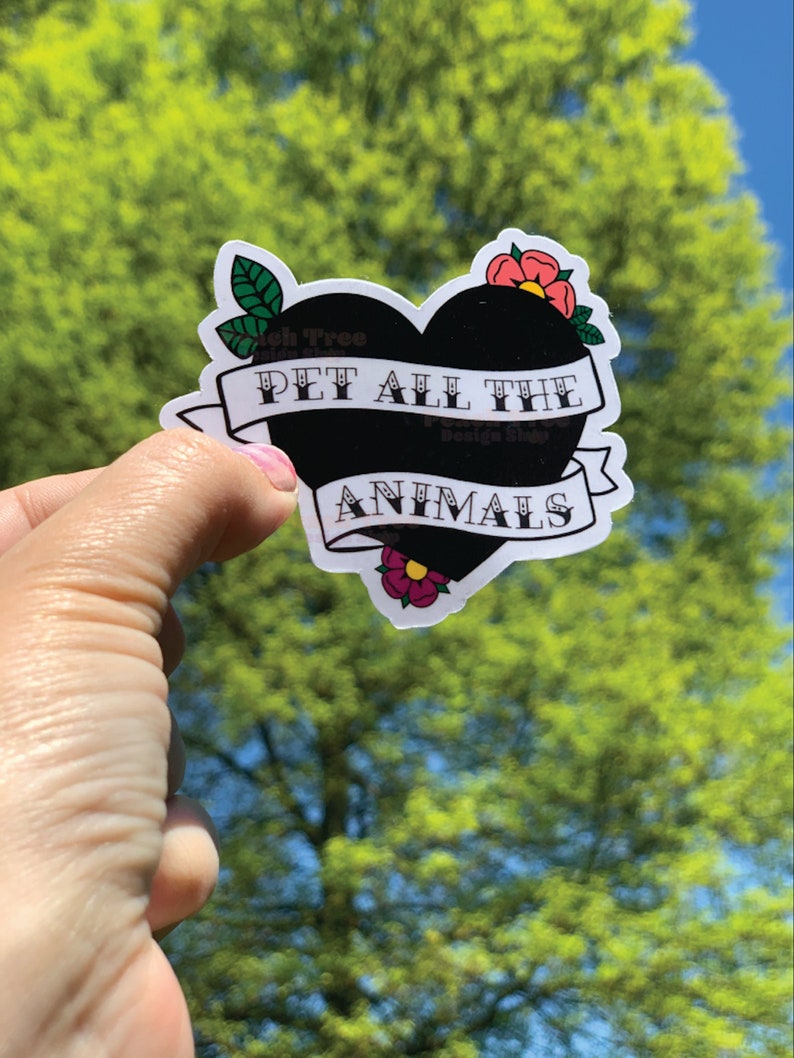 May include: Black heart-shaped sticker with the text "PET ALL THE ANIMALS" in white lettering. The sticker has a green leaf and two pink flowers on either side.