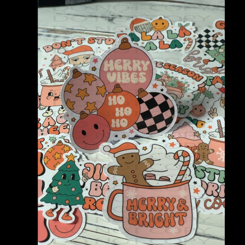 May include: A collection of Christmas-themed stickers featuring a variety of designs, including ornaments, a gingerbread man, a mug with the text "Merry & Bright", and a Christmas tree. The stickers are in a retro style with pink, red, and white colors.