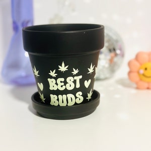 May include: Black ceramic planter with a white design of marijuana leaves and hearts. The text "BEST BUDS" is written in white on the planter.