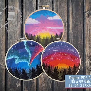 May include: Three round cross-stitch patterns in wooden hoops, each depicting a colorful sunset or night sky scene. The patterns include a sunset, aurora borealis, and starry night. The image includes text that says "Digital PDF Pattern 95 x 95 Stitches 25, 24, 21 Colors."
