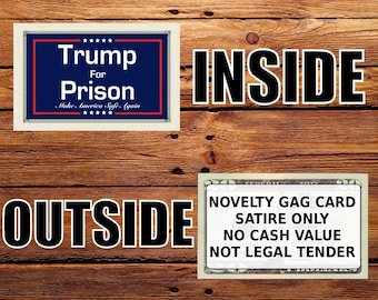 May include: A rectangular card with a blue background, white text reading Trump For Prison, and the phrase Make America Safe Again. A second card features white text on a black border stating NOVELTY GAG CARD, SATIRE ONLY, NO CASH VALUE, NOT LEGAL TENDER.