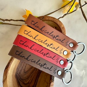 May include: Four leather keychains in brown, orange, red, and dark brown with the text "think celestial" and a small sun graphic on each keychain.