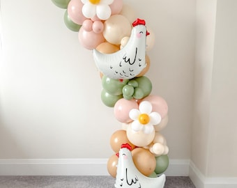 Op de afbeelding: Een ballonslinger met witte kippenvormige ballonnen met rode kammen, afgewisseld met pastelkleurige ballonnen in roze, groen en beige. Witte madeliefvormige ballonnen met gele centra zijn ook inbegrepen.