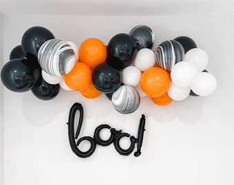 May include: A Halloween balloon garland with black, orange, and white balloons. The garland is decorated with black and white marbled balloons. The word "boo!" is spelled out in black balloons.