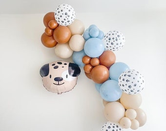 May include: A balloon garland with brown, beige, and blue balloons. Some of the balloons have a paw print pattern. There is also a foil balloon shaped like a dog's head.