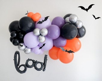 May include: A Halloween balloon garland with black, purple, orange, and silver balloons. The garland is decorated with black bats and the word "boo!" is spelled out in black balloons.