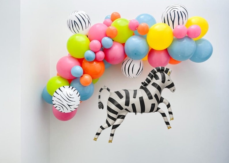 May include: A colorful balloon arch with black and white zebra print balloons and a zebra balloon animal.