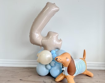 May include: A beige number four balloon with a cluster of blue and beige balloons and a brown inflatable dog with a blue and white striped shirt.