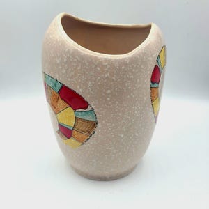 Puede incluir: Un jarrón de cerámica beige con un acabado moteado y un diseño geométrico en tonos de rojo, amarillo, verde y marrón.