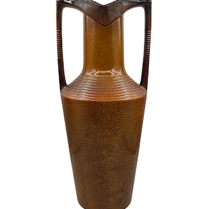 Peut inclure: Un grand vase en céramique marron avec une finition brillante et tachetée. Le récipient présente deux hautes anses arquées reliées au col, une ouverture étroite et une série de stries horizontales entourant l'épaule au-dessus du corps principal.