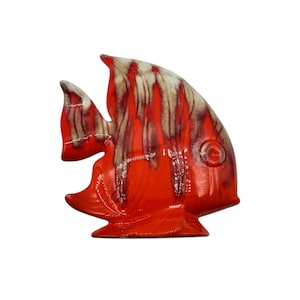 May include: A ceramic fish ornament in a bright red colour with a glossy finish. The fish has a distinctive design with brown and cream-coloured accents on its fins and upper body. The ornament is a decorative item, suitable for home decor.