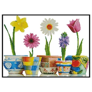 May include: A collection of six colorful flower pots with different floral arrangements. The pots are decorated with various patterns and designs, including blue and white, yellow and green, and red and white. The flowers include a yellow daffodil, a pink gerbera daisy, a white daisy, a purple hyacinth, and a pink tulip.