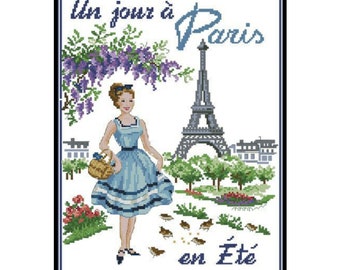 May include: A cross-stitch pattern featuring a woman in a blue dress standing in front of the Eiffel Tower with the text "Un jour à Paris en Été".